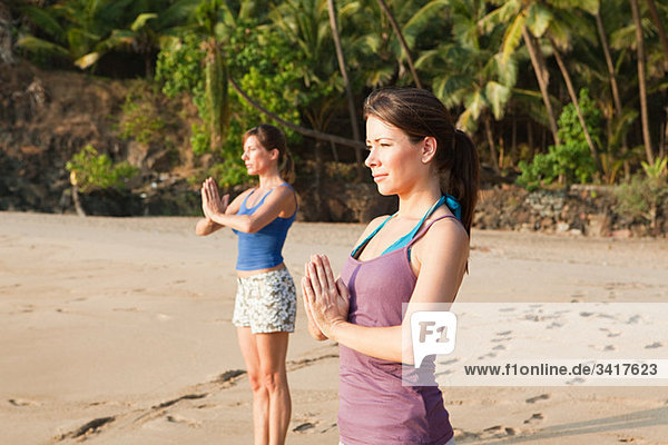 Women practicing yoga on a beach