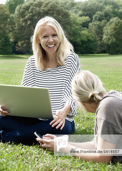 Happy friends with computer in the park