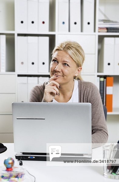 Woman sitting by desk with laptop
