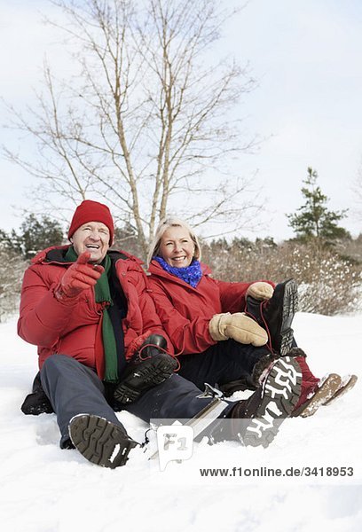 Zwei Senioren sitzen im Freien im Schnee.
