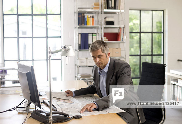 Businessman reading a newspaper at his desk