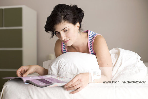 Frau liest eine Zeitschrift im Bett  Flachwinkelansicht