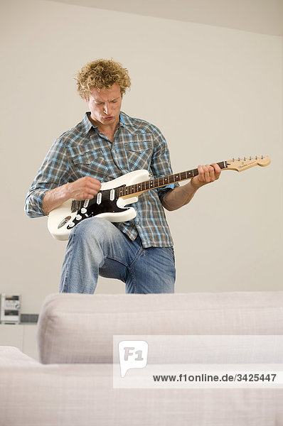 Mann spielt E-Gitarre in der Wohnung  Flachwinkelansicht