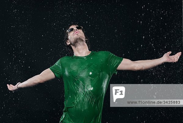 Man standing in rain  stretching arms.
