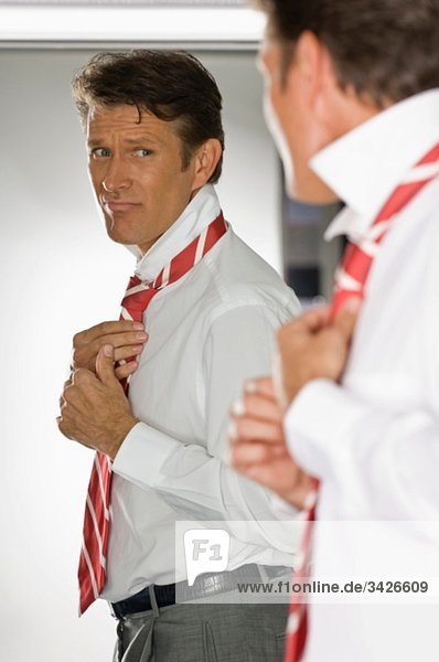 Geschäftsmann vor dem Spiegel stehend  Krawatte bindend