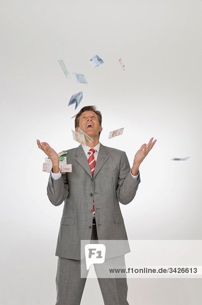 Geschäftsmann wirft Euro-Banknoten in die Luft  schaut nach oben  Porträt