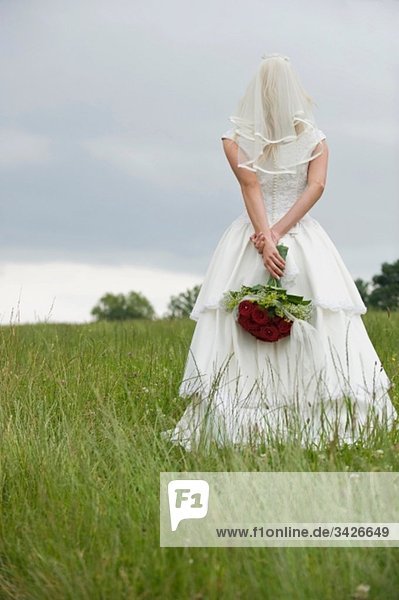 Rückansicht einer Braut mit einem Blumenstrauß.