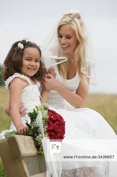 Braut sitzend mit Blumenmädchen (4-5)  lächelnd