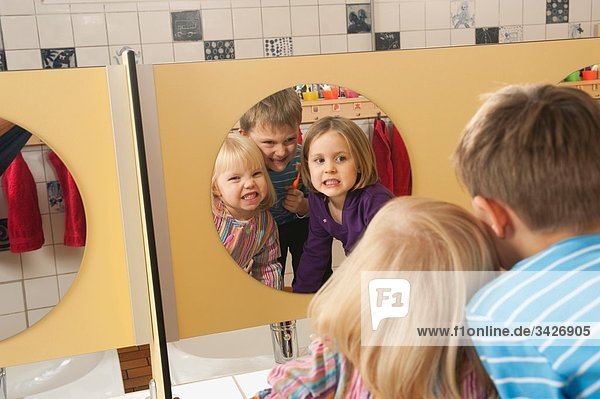 Deutschland  Drei Kinder in der Toilette  Junge (4-5) mit Zahnbürste  Portrait