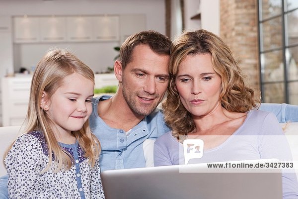 Deutschland  Köln  Familie auf Sofa mit Laptop  Portrait