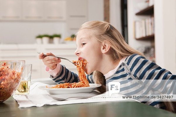 Girl (6-7) eating spaghetti  side view  portrait
