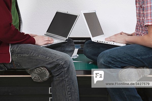 Männer sitzen auf dem Schreibtisch mit dem Laptop.
