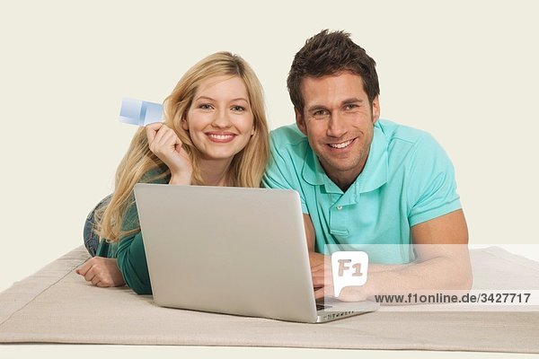 Couple lying and using laptop  smiling  portrait