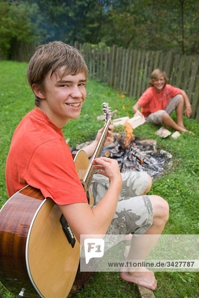 Austria  Salzburger Land  Teenage boys (14-15) in garden  sitting at campfire