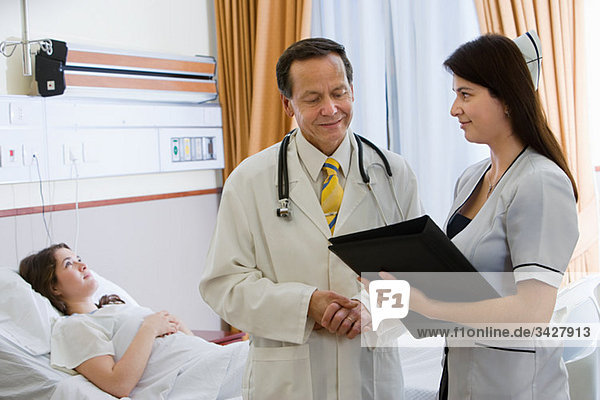Junge Frau im Krankenhauszimmer mit Arzt und Krankenschwester
