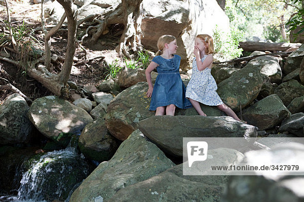 Zwei Mädchen auf Felsen von river