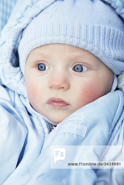 Baby mit blauer Jacke und Mütze  Porträt