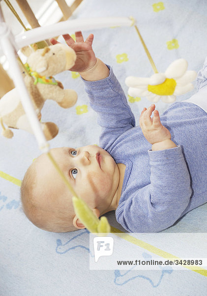 Baby im Kinderbett greift nach hängendem Spielzeug  Erhöhte Ansicht