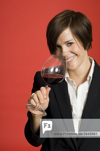 Weibliche Sommelier tasting Wein vor rotem Hintergrund  Lächeln  portrait