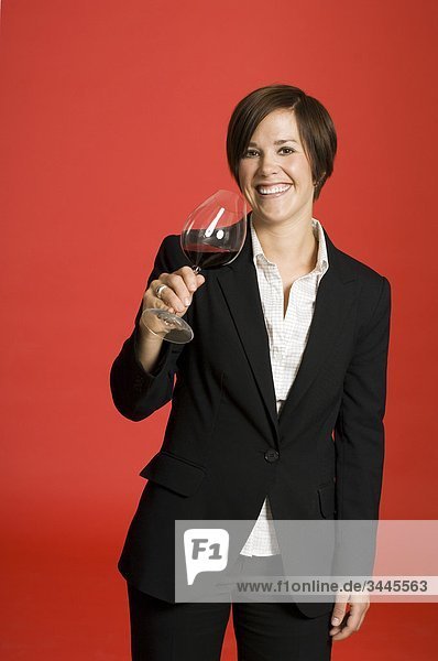 Weibliche Sommelier tasting Wein vor rotem Hintergrund  Lächeln  portrait