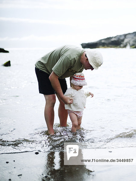 Europa  Spanien  Kanarische Inseln  Teneriffa  Großvater mit Enkelin bei Strand (2-3)