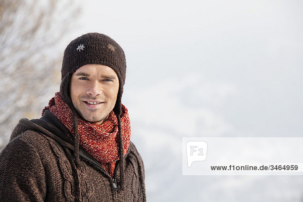 Junger Mann in Winterkleidung lächelnd vor der Kamera