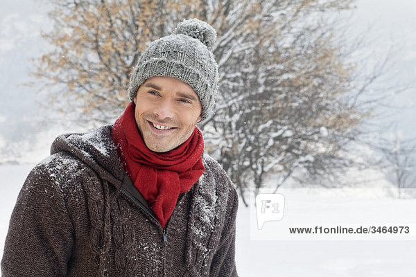 Junger Mann in Winterkleidung lächelnd vor der Kamera