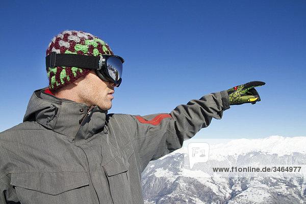 Portrait of young man in ski wear pointing