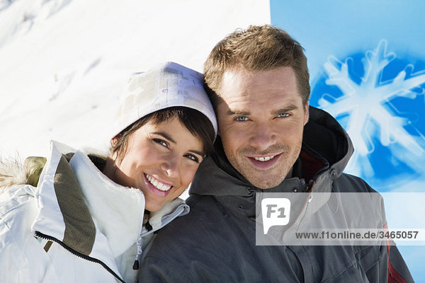 Young couple in winter clothes smiling at camera
