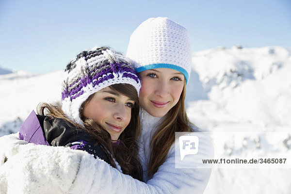 Zwei Teenagermädchen in Winterkleidung  umarmend