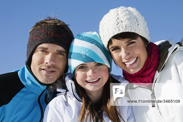 Paar und Tochter in Skikleidung  lächelnd vor der Kamera