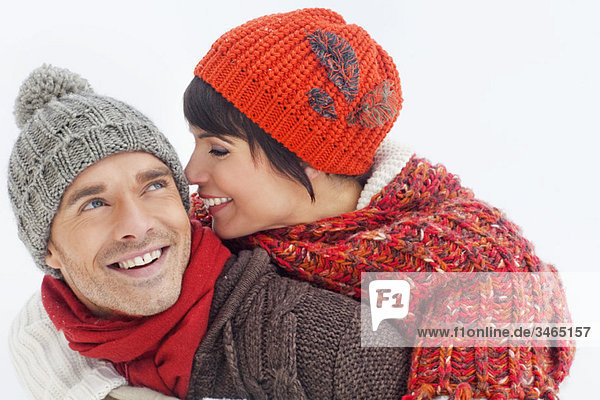 Junger Mann gibt seiner Freundin Huckepack im Schnee