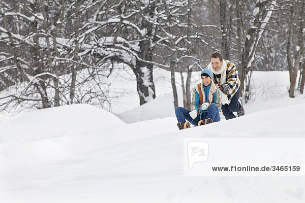 Young man pushing woman on sled