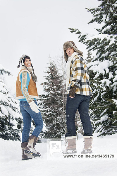 Young couple walking in snow  looking back
