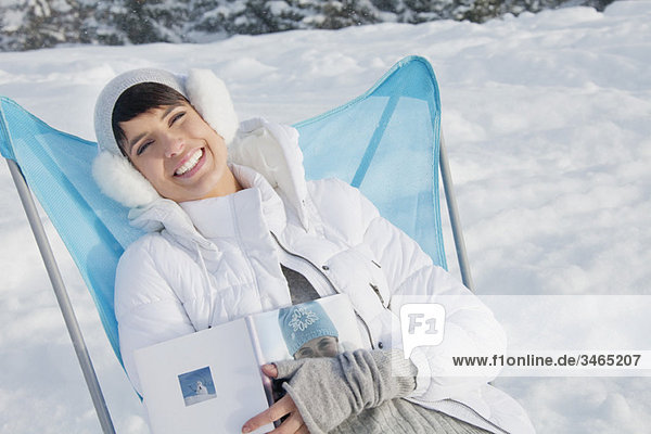 Junge Frau im Schnee ruhend  lächelnd vor der Kamera