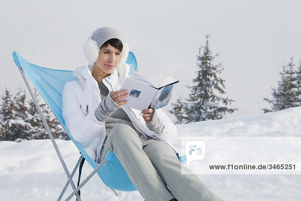 Young woman reading in snow