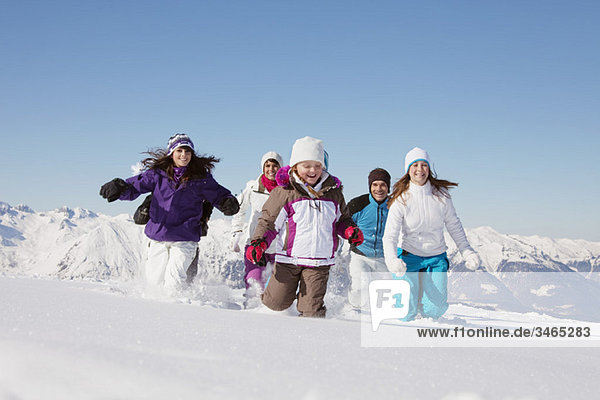 Glückliche Familie beim Laufen im Schnee