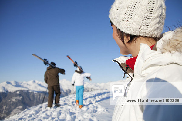 Woman looking at father and daughter carrying skis
