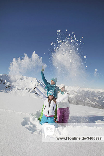 Paar und Tochter in Skibekleidung  Schnee in die Luft werfen
