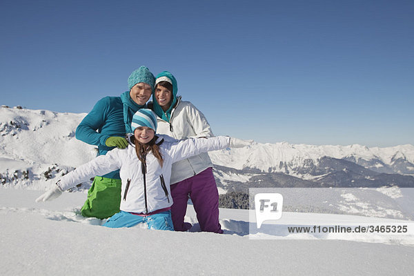 Paar und Tochter in Skibekleidung  spielen im Schnee