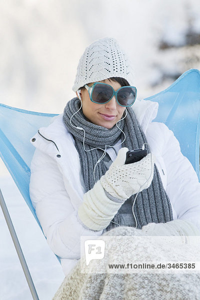 Young woman listening to MP3 player in snow