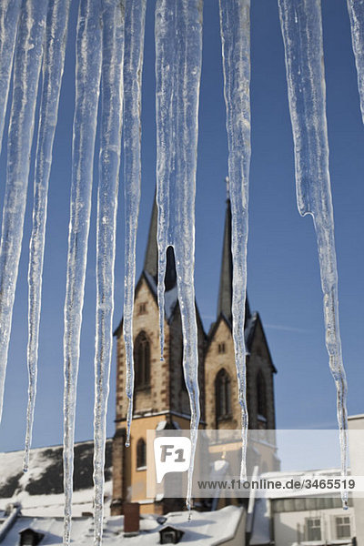Detail von Eiszapfen und einer Kirche im Hintergrund
