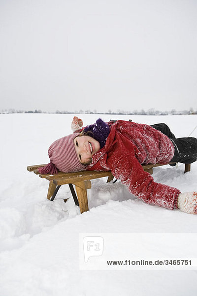 A young girl lying on a sled