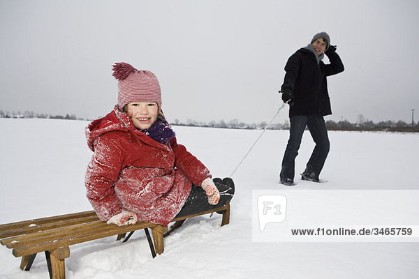 A man pulling a sled daughter on it