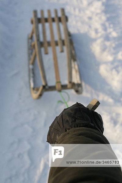 A hand pulling a sled in snow