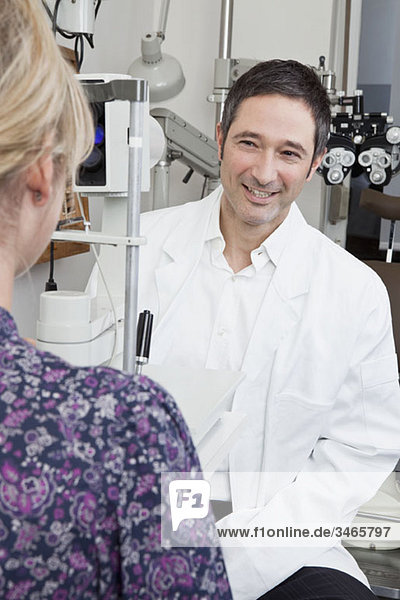 Ein Augenarzt  der eine Spaltlampen-Biomikroskop-Untersuchung an einem Patienten durchführt.