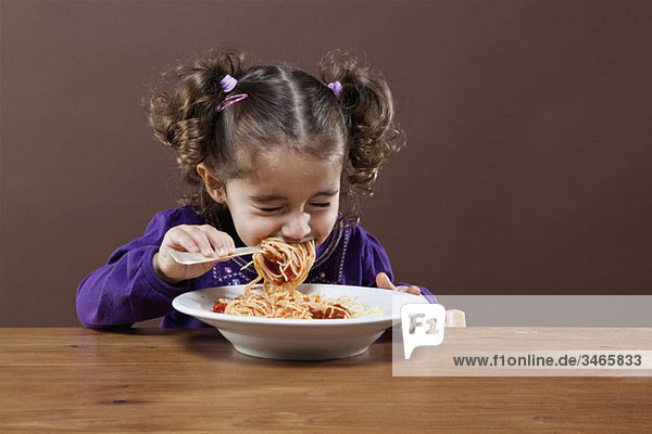 Ein junges Mädchen mit geschlossenen Augen isst Spaghetti  Studioaufnahme