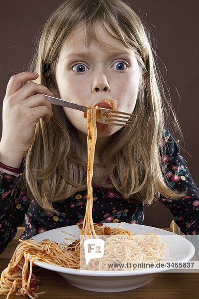 A young girl eating spaghetti messily  studio shot
