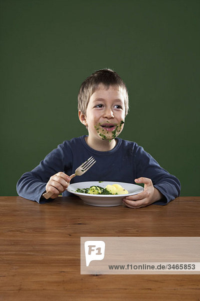 Ein fröhlicher Junge  der sich beim Essen das ganze Gesicht voll frisst.