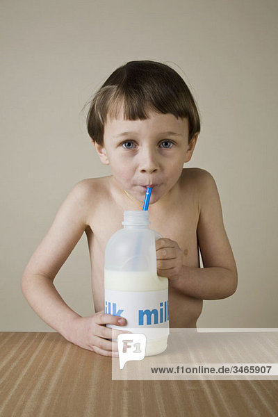 Ein Junge  der eifrig Milch aus einem Krug trinkt.